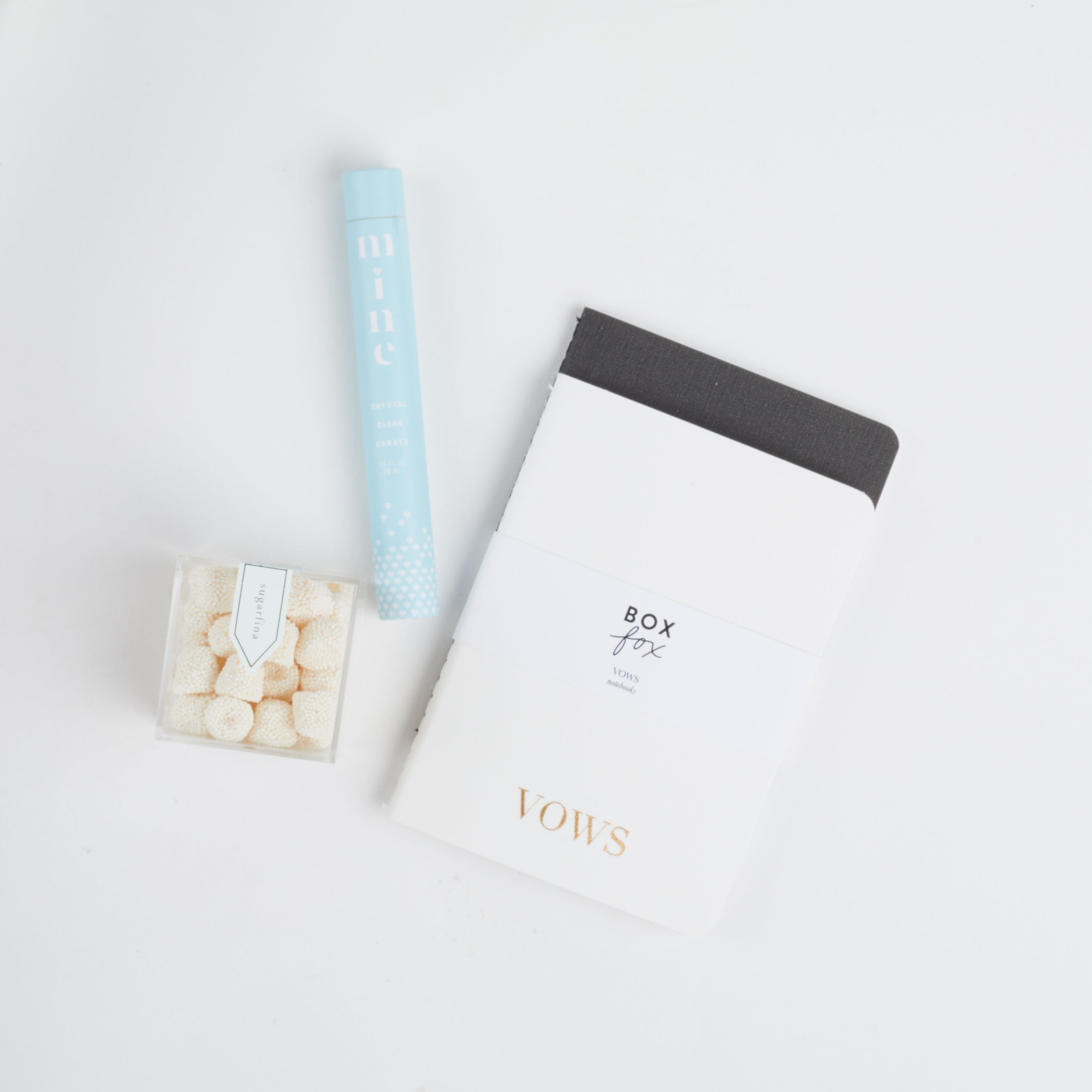 Sugarfina Champagne Bubbles, BOXFOX x Appointed Co. VOW Notebooks and Mine Co Ring Cleaning Pen laid out on white background