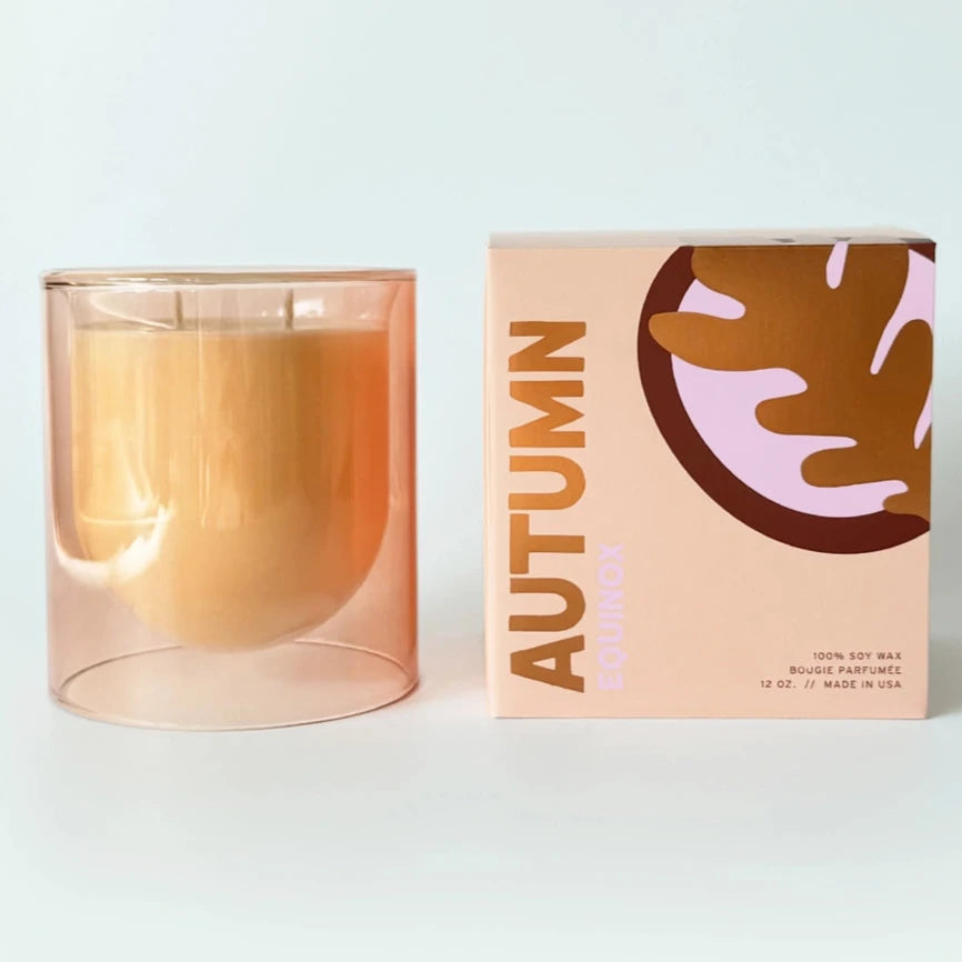 clear glass taupe candle next to packaging that says 'AUTUMN'