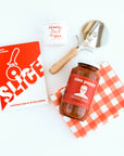 "Slice" Pizza book, wood pizza cutter, Ciao Pappy Marinara sauce, Pizza herbs jar and plaid red Geometry tea towel.