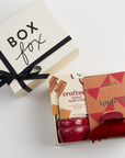 Apple pie chocolate bar, 2 spiked apple cider cocktail sachets, apple cider mini tin candle, and red claw clip packed in creme BOXFOX