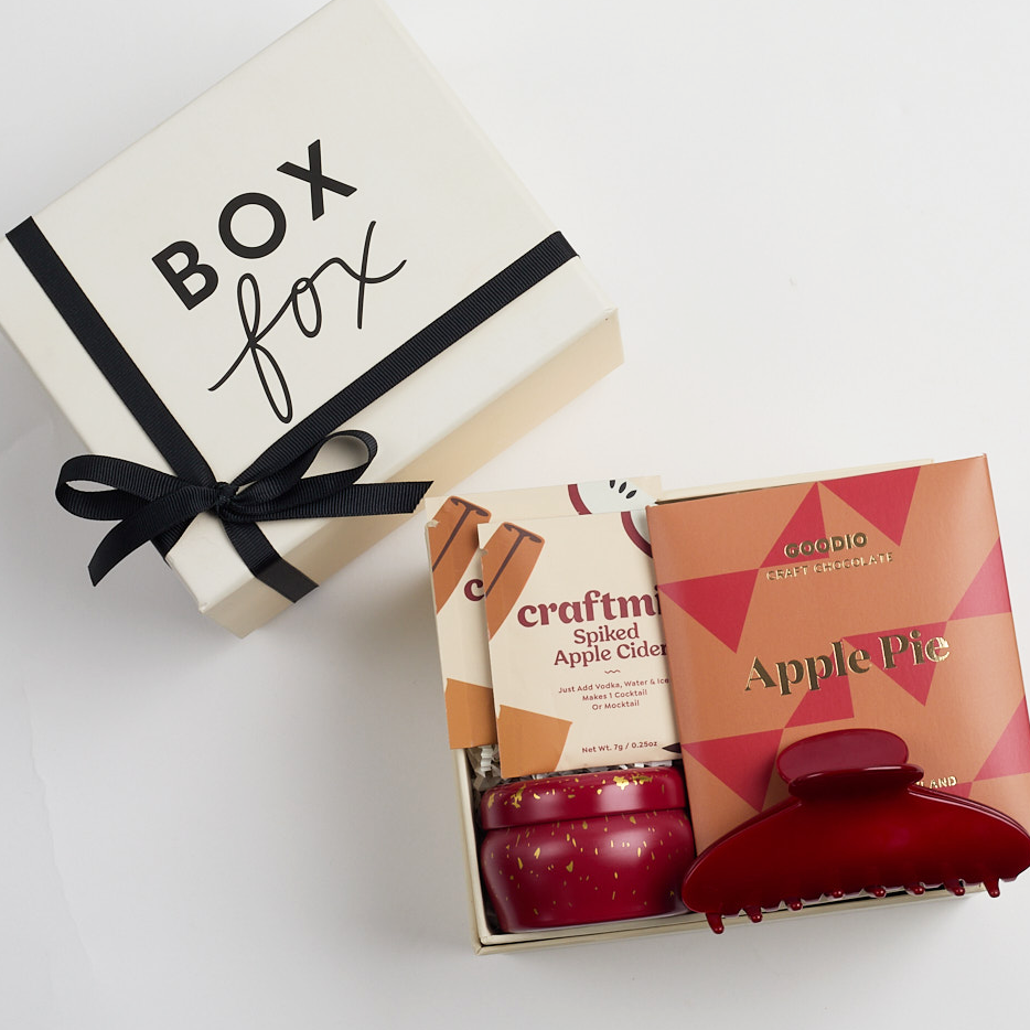 Apple pie chocolate bar, 2 spiked apple cider cocktail sachets, apple cider mini tin candle, and red claw clip packed in creme BOXFOX