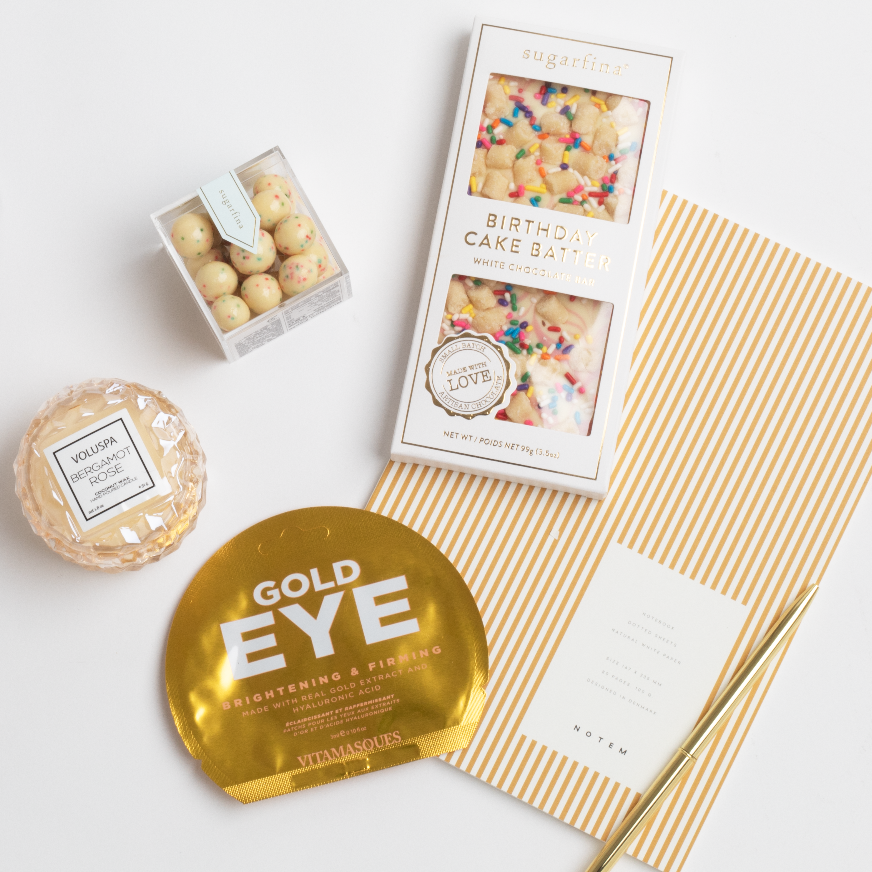 contents of BOXFOX Birthday Gift Box: Sugarfina Birthday Cake Batter Chocolate Bar, Notem Ochre Lines Notebook, Voluspa Bergamot Rose Macaron Candle, Vitamasques Gold Eye Pads, Sugarfina Birthday Cake Cookies, BOXFOX Gold Bullet Pen