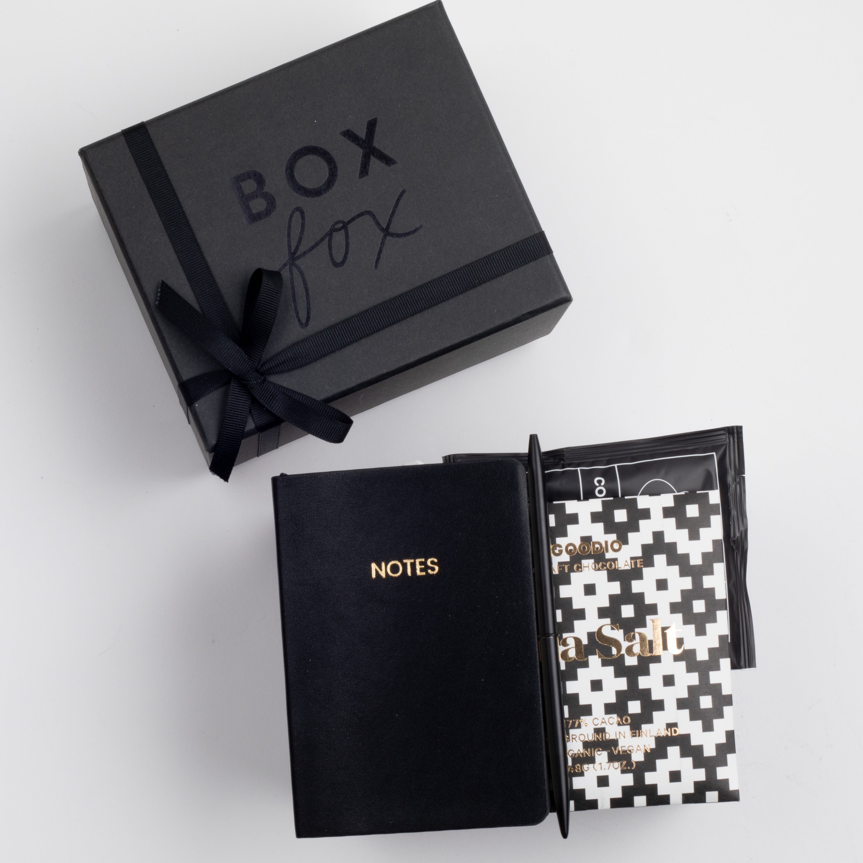 BOXFOX Black Matte Gift box with Black A6 Vegan Leather Notebook, black bullet pen, Goodio Sea Salt Chocolate Bar, and a single Copper Cow Pour Over Latte Packet