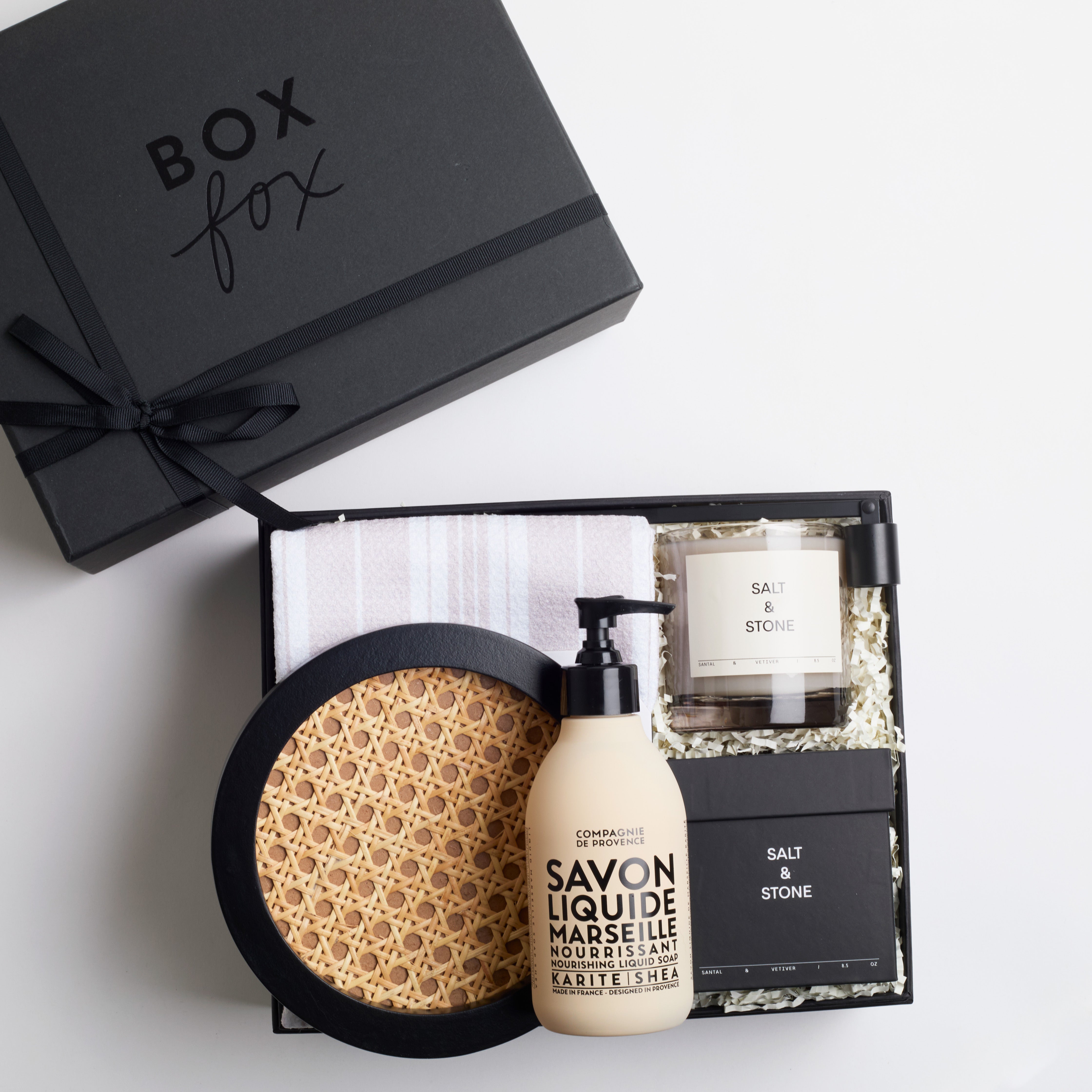 BOXFOX Housewarming Gift Box with a rattan tray, tea towel, hand soap, a candle, and a candle snuffer