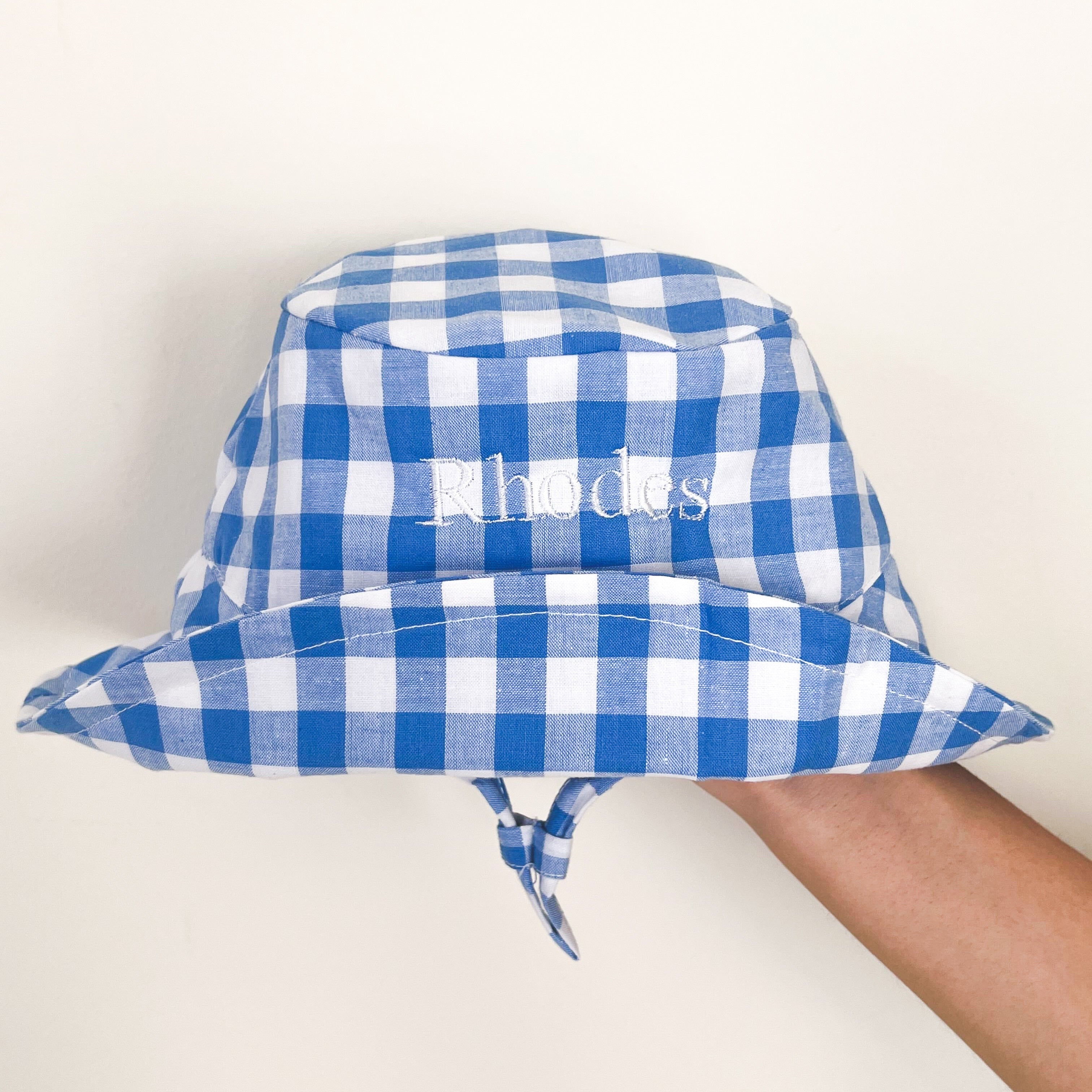 embodied gingham blue and white hat. embroidered text is in white 