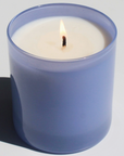 purple glass candle burning behind white background