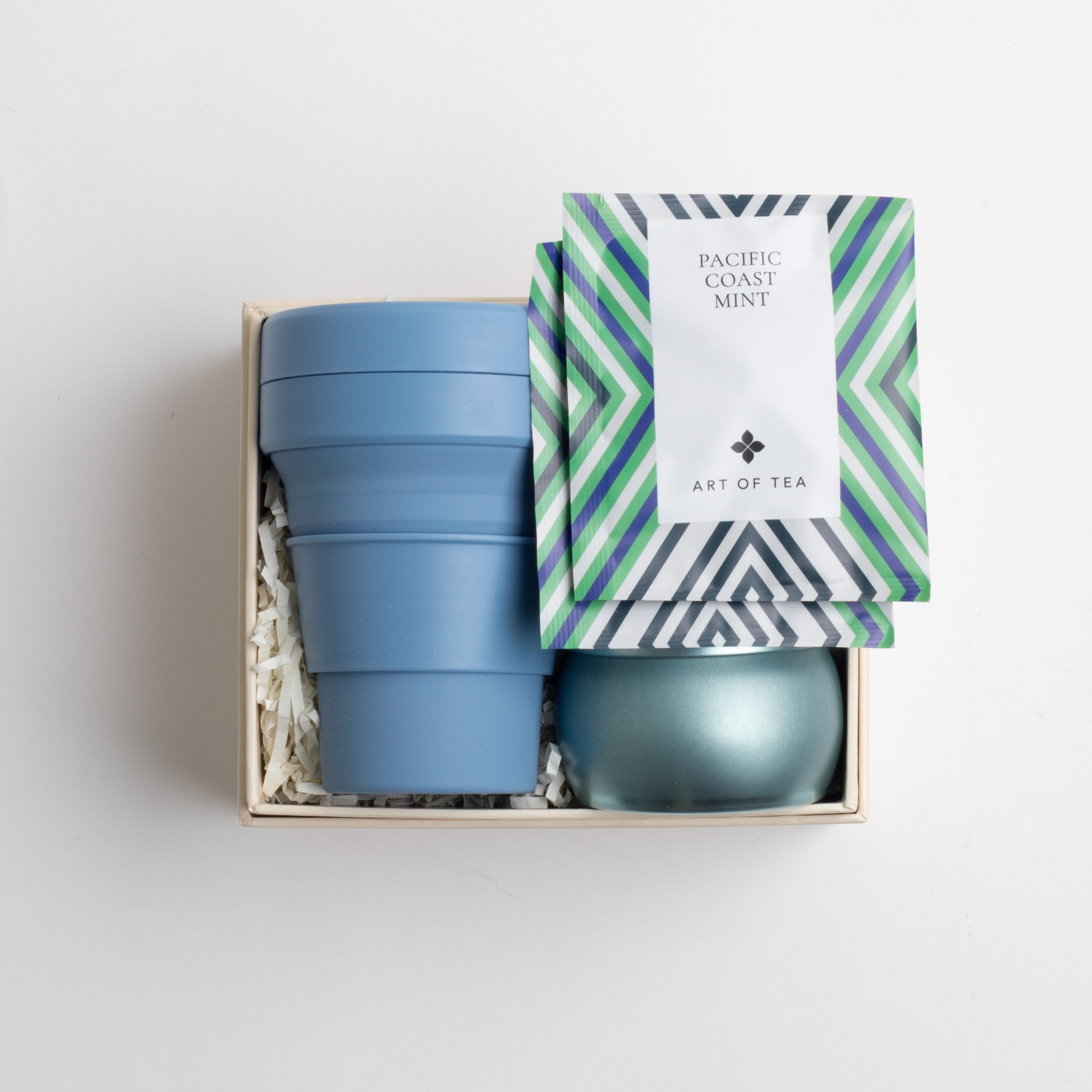 Open BOXFOX box with cup, candle and tea sachets, on white background.